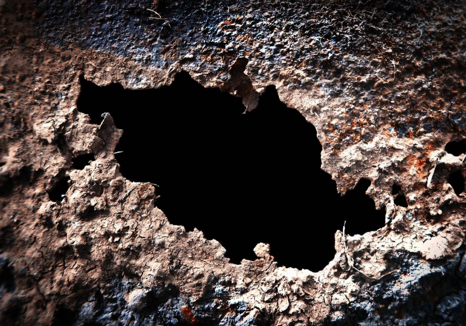 Close-up of a rust hole eaten through a car body panel
